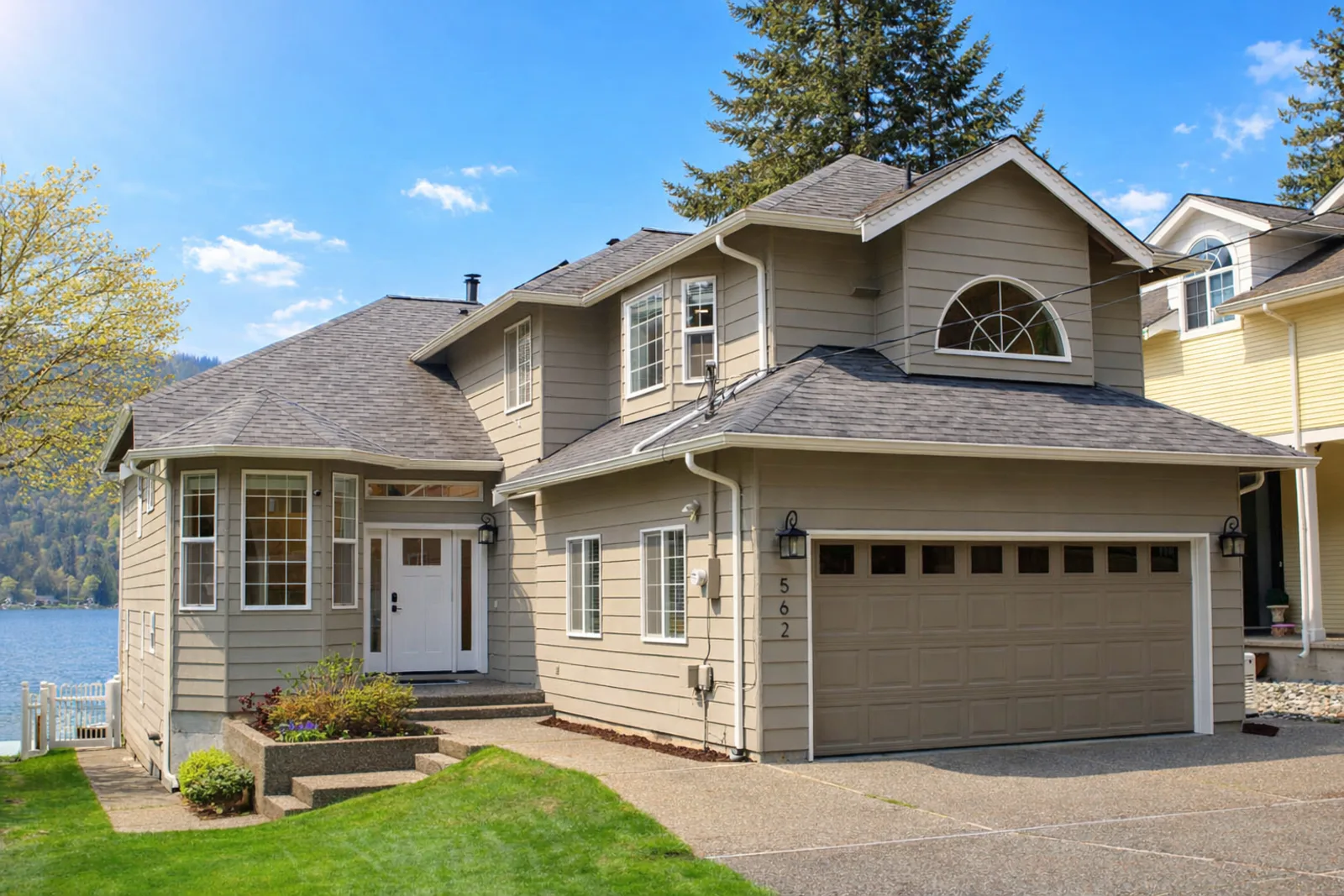 Exterior of 562 West Lake Samish Drive waterfront home — bright blue sky, lake visible in the background